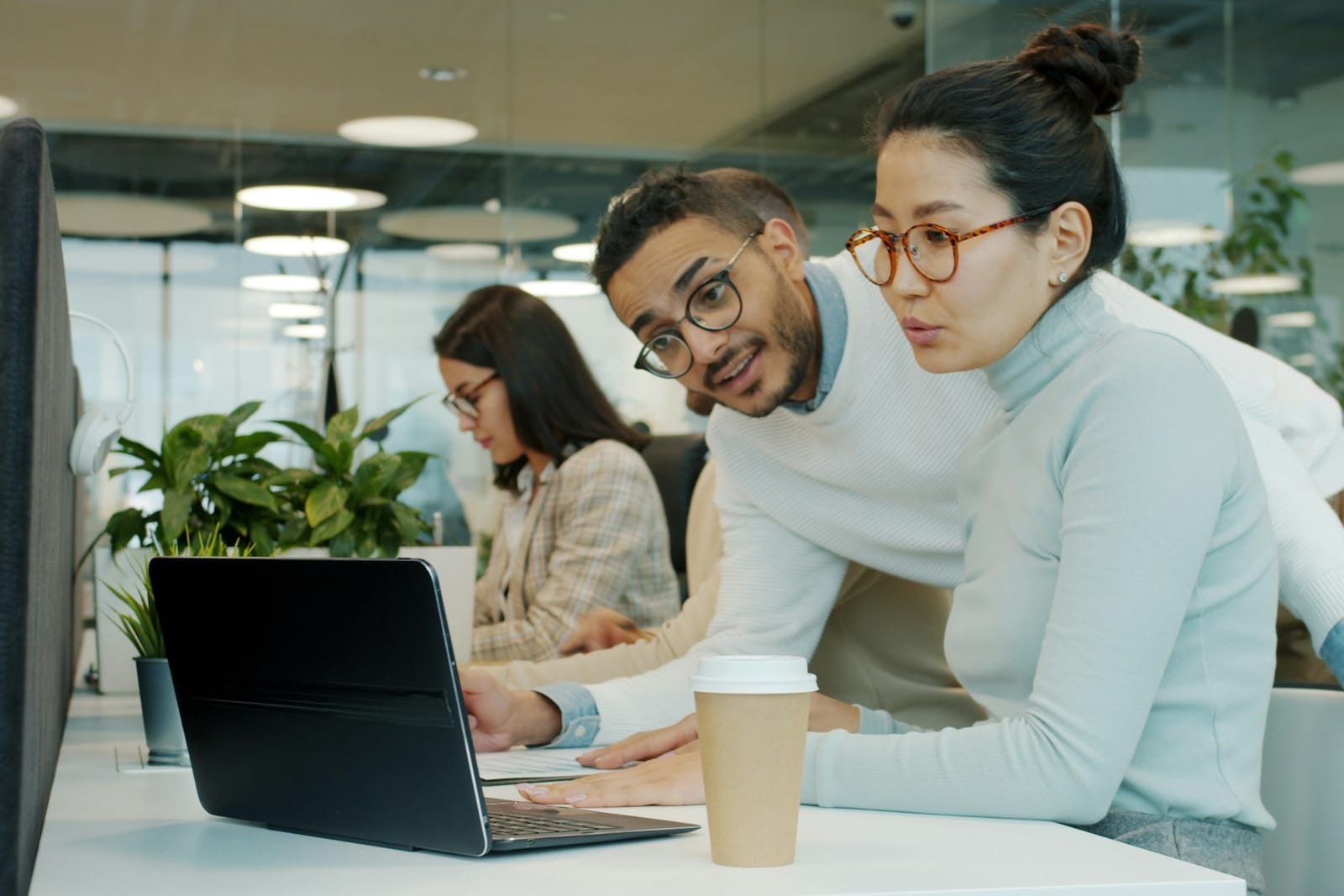 Systems integration and safeguards Two colleagues reviewing work together on a laptop in an open-plan office